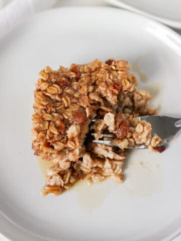 Baked Banana Nut Oatmeal on a white plate with maple syrup