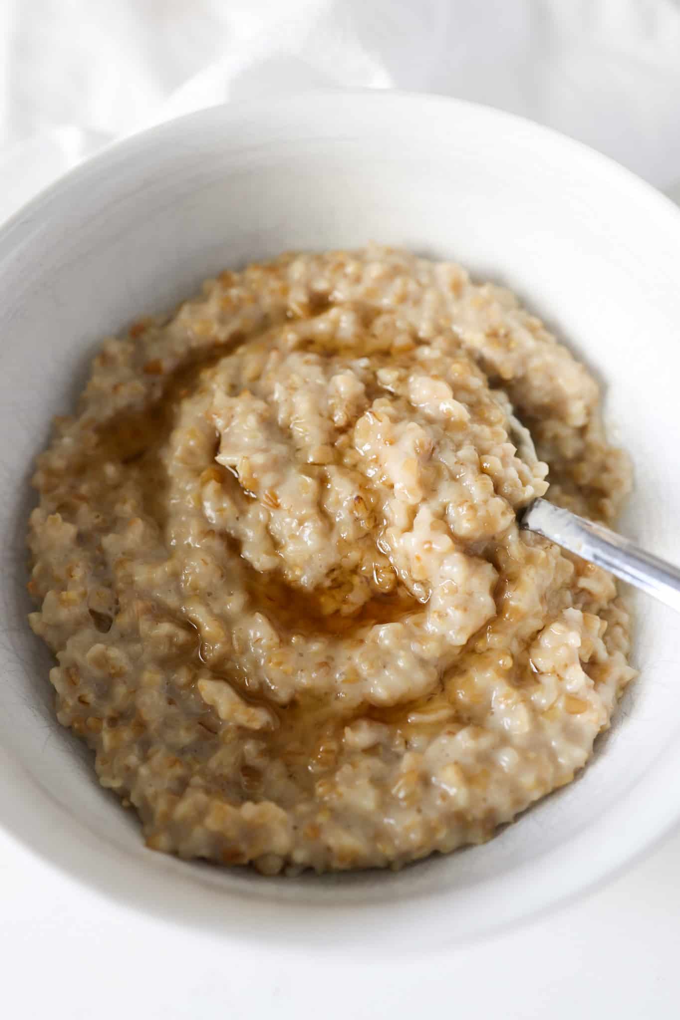 Creamy Steel Cut Oatmeal with Maple Syrup in a white bowl.